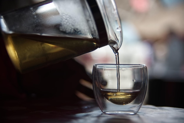 Le thé se verse dans un verre transparent avec un arrière-plan flou à bulles