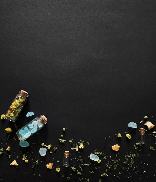 Thé sec et cristaux de sucre dans des bouteilles en verre sur fond sombre