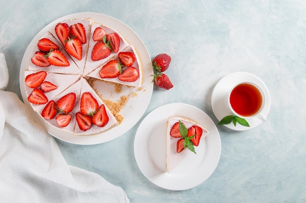 Thé sucré pour le petit-déjeuner et délicieux gâteau au fromage avec des fraises fraîches et une recette maison à la menthe sans cuisson sur une table en pierre bleue Copier l'espace