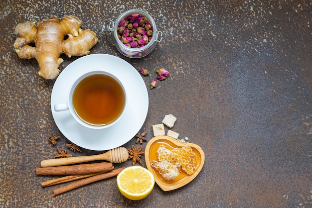 Thé, tasse de thé, feuilles de thé séchées avec théière et herbes, miel, gingembre sur fond sale grunge