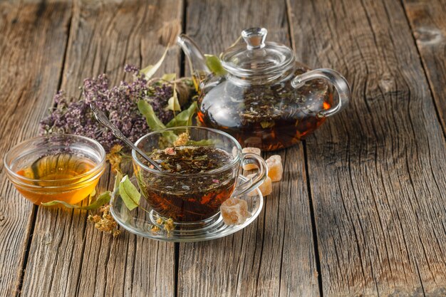 Thé utile fraîchement préparé avec des fraises des bois séchées dans une théière en verre et une tasse sur une table en bois