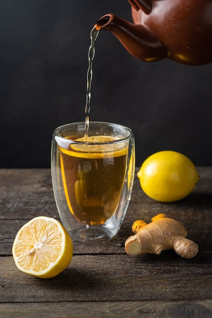 Thé versé dans un verre, un citron, une surface de gingembre derevyannogm.