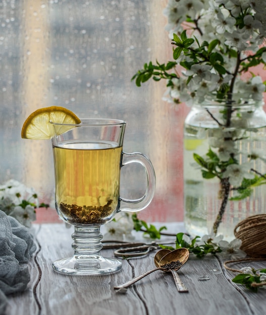 Thé vert frais. Tasse à thé avec des feuilles de thé vert sur la table en bois. Thé au citron