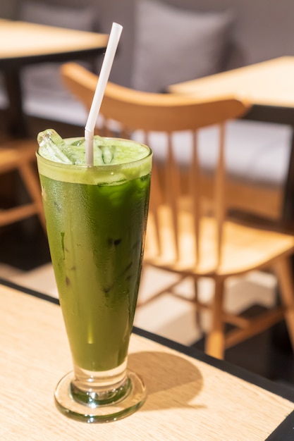 le thé vert glacé contient dans un grand verre en forme de V avec un environnement de café