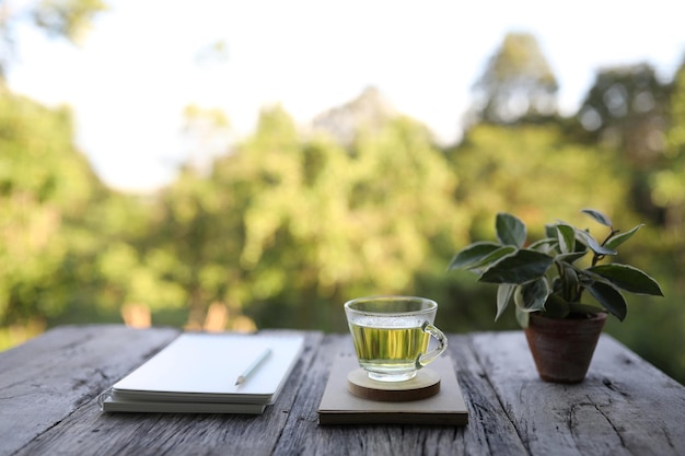 Thé vert et Hoya Carnosa avec carnet et crayon sur table en bois