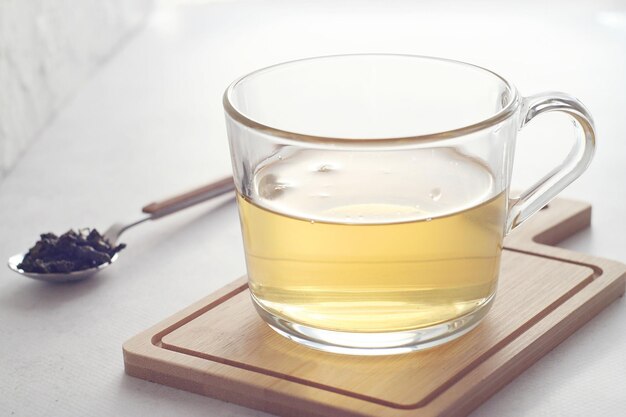 Thé vert lait chinois oolong dans une tasse transparente sur la table Derrière se trouve une cuillère à café de feuilles de thé Reste