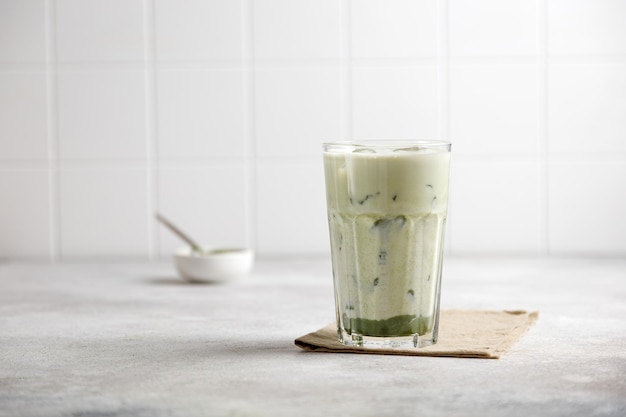 Thé vert matcha glacé avec du lait et de la glace sur une table grise