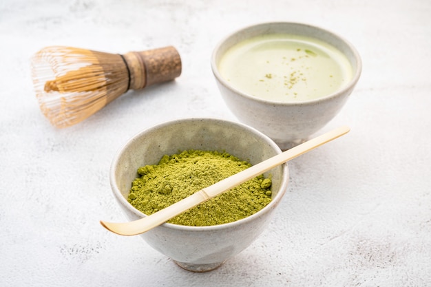 Thé Vert Matcha En Poudre Avec Installation De Brosse Fouet En Bambou Matcha Sur Fond De Béton Blanc