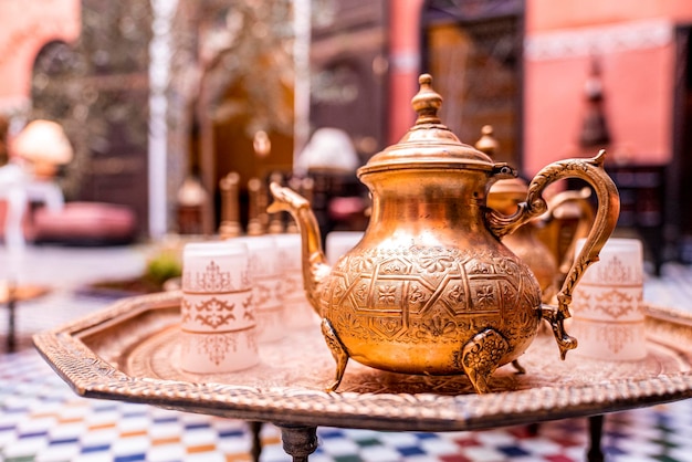 Théière en cuivre ornée traditionnelle avec des verres sur la table