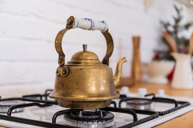 Théière en cuivre vintage sur une cuisinière à gaz.