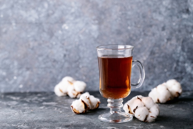 Une théière en métal noir et une tasse de thé dans une tasse en verre