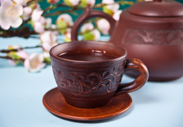 Théière et tasse en céramique marron avec du thé. Sakura branche de fleur de cerisier en arrière-plan. Style oriental asiatique.