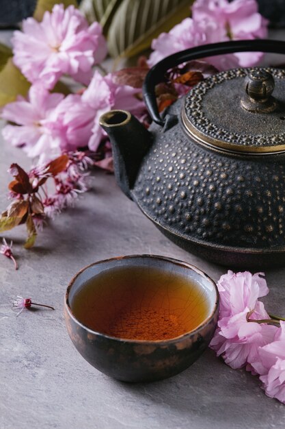 Théière et tasse de thé avec une branche de fleur