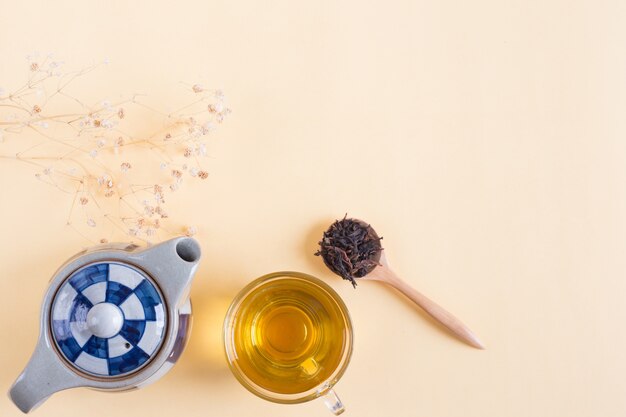 Théière avec une tasse de thé et livre avec fleur séchée