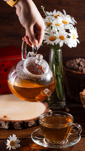 Une théière et une tasse de thé sur une table en bois et un bouquet de marguerites