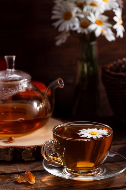 Une théière et une tasse de thé sur une table en bois et un bouquet de marguerites