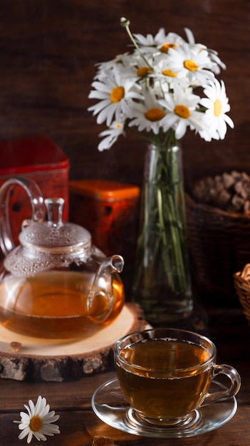 Une théière et une tasse de thé sur une table en bois et un bouquet de marguerites