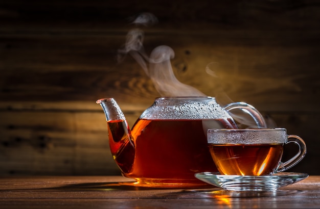 Théière et tasse en verre sur le fond en bois