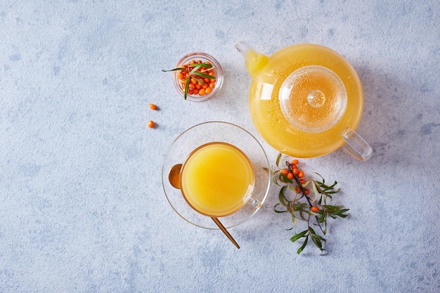 Théière en verre avec du thé à l'argousier sur fond clair