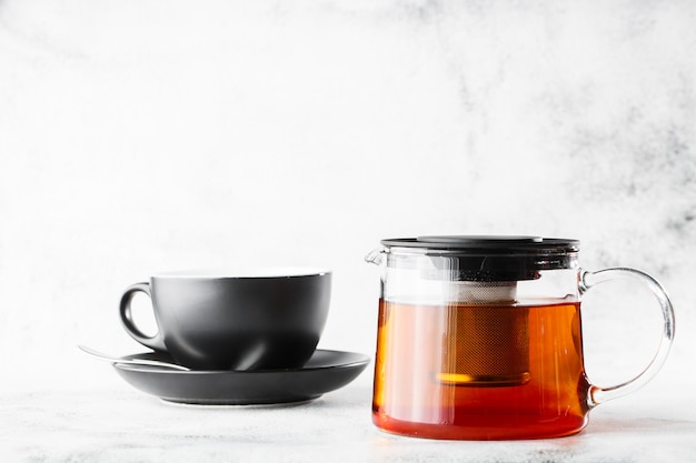 Théière en verre avec une tasse sombre de thé noir isolé sur fond de marbre brillant. Vue aérienne, espace copie. Publicité pour le menu du café. Menu du café. Photo horizontale.