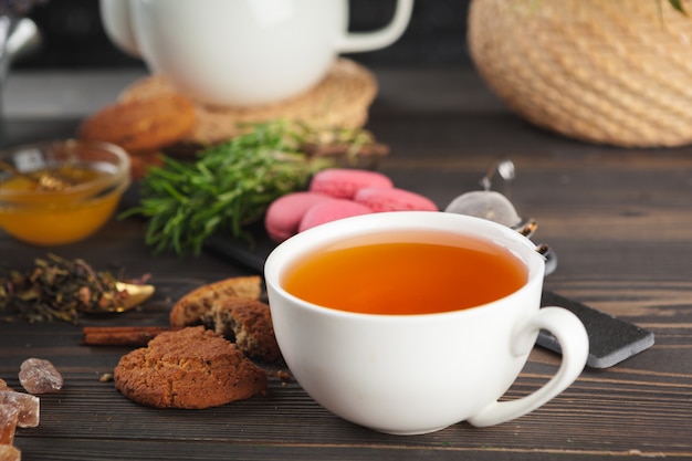 Théière en verre avec une tasse de thé noir sur une table en bois