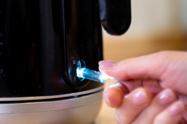 Une théière versant de l'eau bouillante dans une tasse un sachet de thé noir est mis dans une tasse