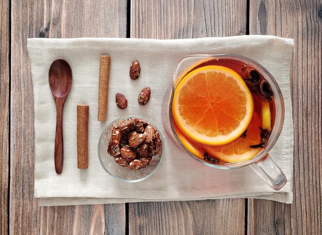 Théière de vin chaud aux épices et agrumes, amandes épicées, bâtons de cannelle, cuillère en bois