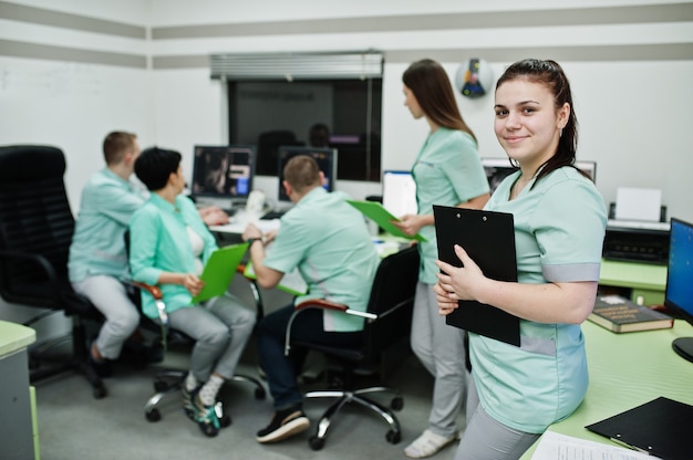 Thème médical. Portrait d'une femme médecin avec presse-papiers contre un groupe de médecins réunis au bureau de l'irm au centre de diagnostic de l'hôpital.