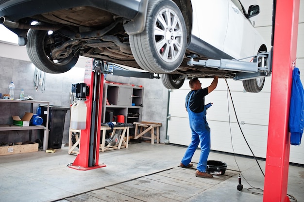 Thème de réparation et d'entretien de voiture. Mécanicien en uniforme travaillant dans le service automobile.