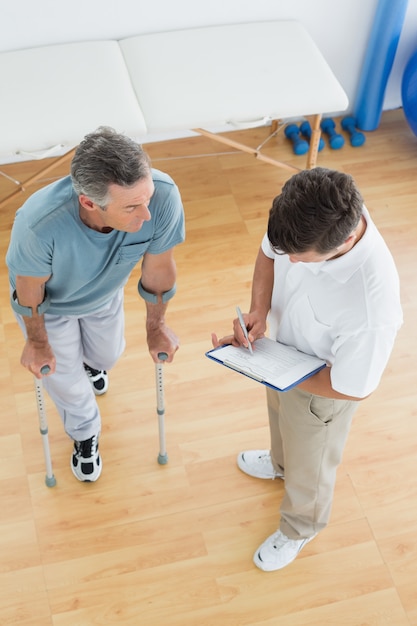 Thérapeute discutant des rapports avec un patient handicapé dans un hôpital de gym