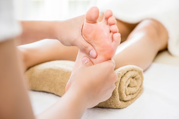 Photo thérapeute donnant un massage relaxant des pieds thaïlandais à une femme dans un spa