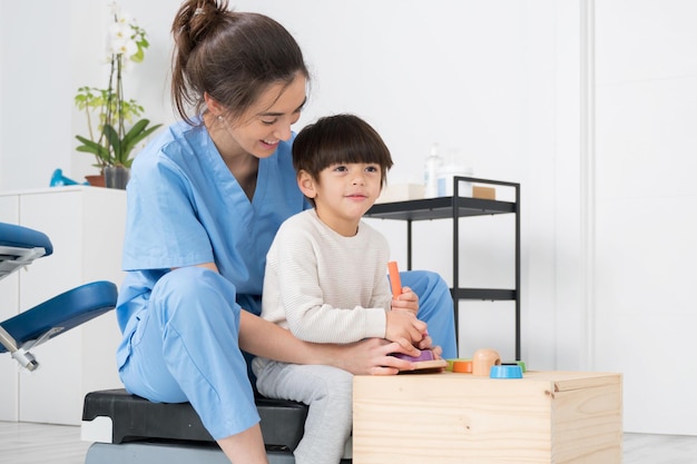 Thérapeute faisant des activités de développement avec un petit garçon atteint de paralysie cérébrale en réadap...