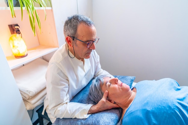 Un thérapeute fait un massage oriental du cou à une femme mature.