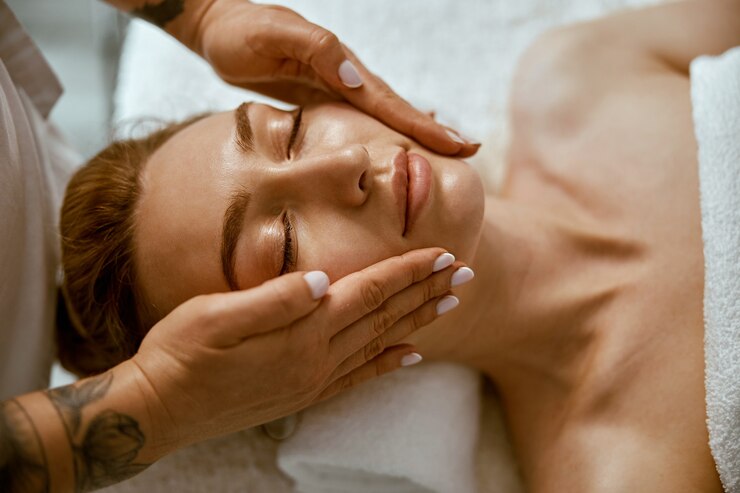 Le thérapeute fait un massage relaxant du visage à une jeune femme dans un cabinet de bien-être moderne