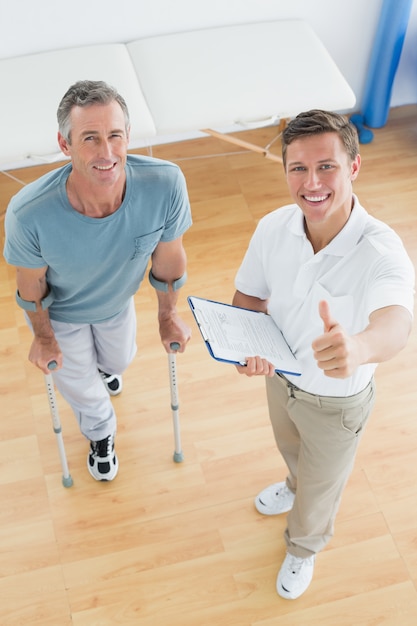 Thérapeute gesticulant pouce en l&#39;air avec un patient handicapé