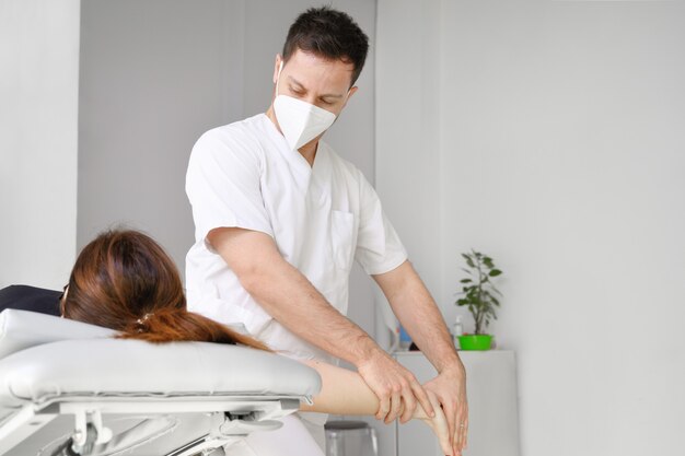 Thérapeute masculin donnant un massage pour soulager la douleur à l'épaule à une patiente dans une clinique de physiothérapie.