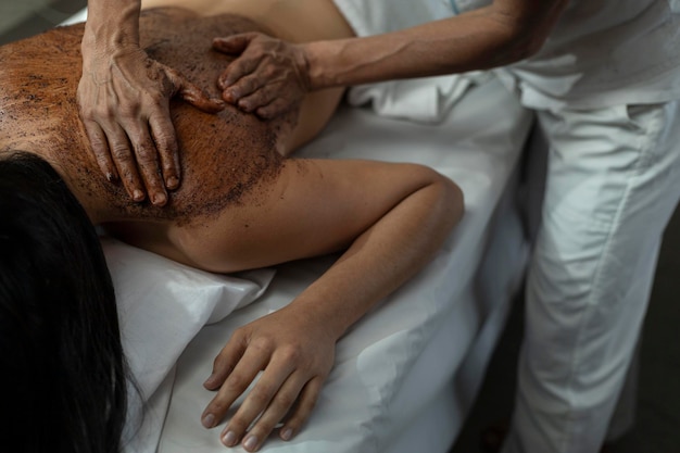 Thérapie de cacao appliquée sur le dos d'une jeune femme latino-américaine dans un spa