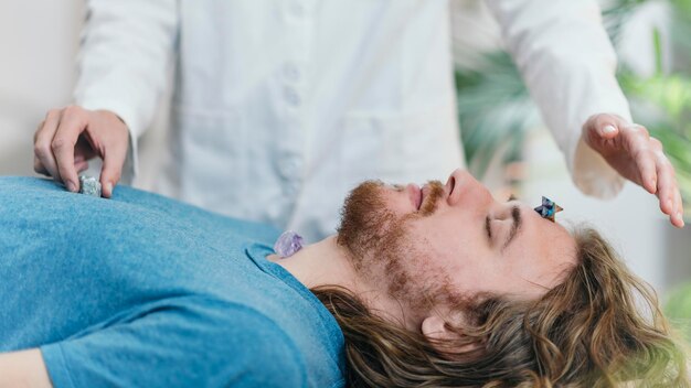 Photo thérapie de cristal avec un jeune homme allongé sur une table de massage