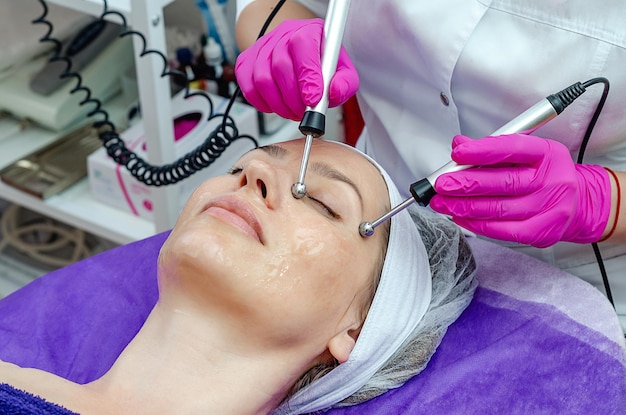 Thérapie par micro-courant pour le visage d'une femme dans un salon de beauté spa Boules métalliques sur tiges Procédure électro moderne