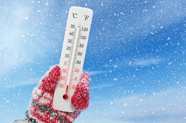 Photo thermomètre blanc celsius et fahrenheit à la main température ambiante moins 26 degrés celsius