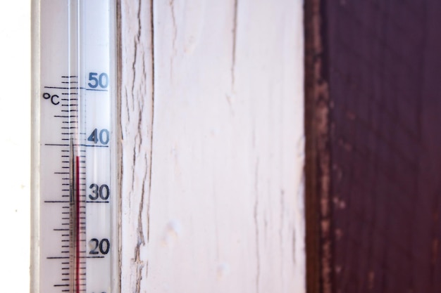 Un thermomètre Celsius sur un cadre de fenêtre d'une maison de campagne indique des températures jusqu'à 38 degrés à l'extérieur
