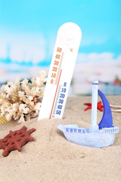 Thermomètre dans le sable sur fond clair