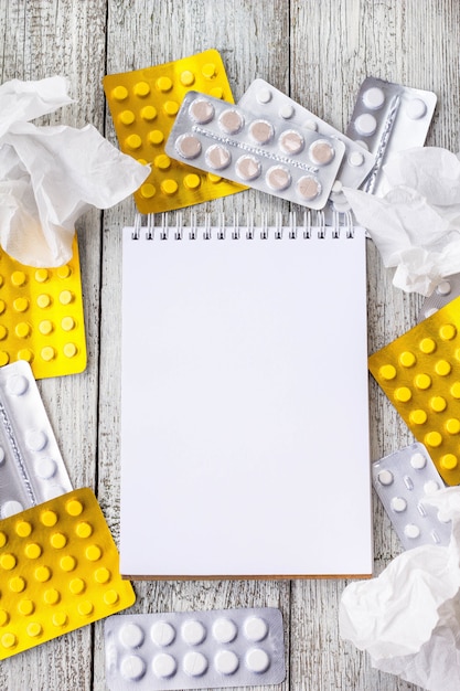 Photo thermomètre et pilules avec cahier vierge sur table en bois blanc