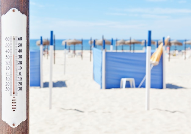 Photo un thermomètre sur la plage en été, dans le mur de chaises longues et de parasols.