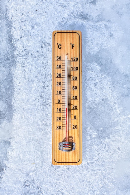 Thermomètre posé sur la glace, indiquant moins 5 degrés. Soleil qui brille de côté. Hiver / basses températures à venir, concept.
