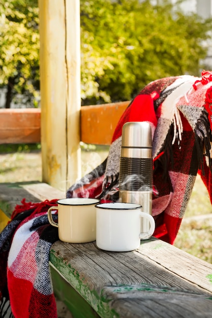 Thermos avec thé chaud sur une table en bois.