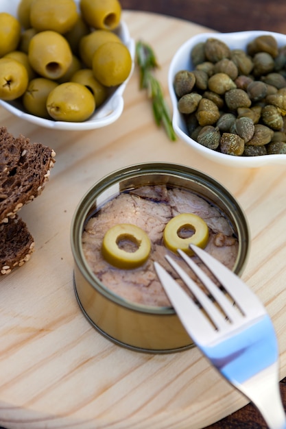 Thon peut à côté d&#39;un bol d&#39;olives et de câpres