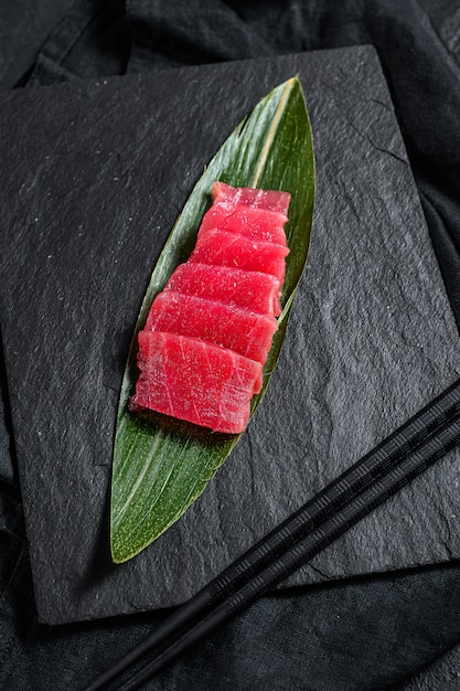 Thon sashimi cru frais sur une planche en pierre. Fond noir. Vue de dessus