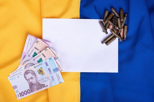 Tient des billets de hryvnia et des douilles dans ses mains sur un fond divisé par deux par un espace de copie de drapeau ukrainien bleu et jaune