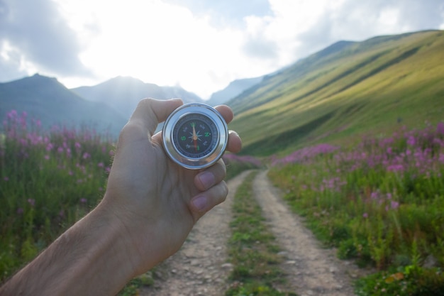 Photo tient une boussole sur le fond d'une montagne et d'un chemin de terre